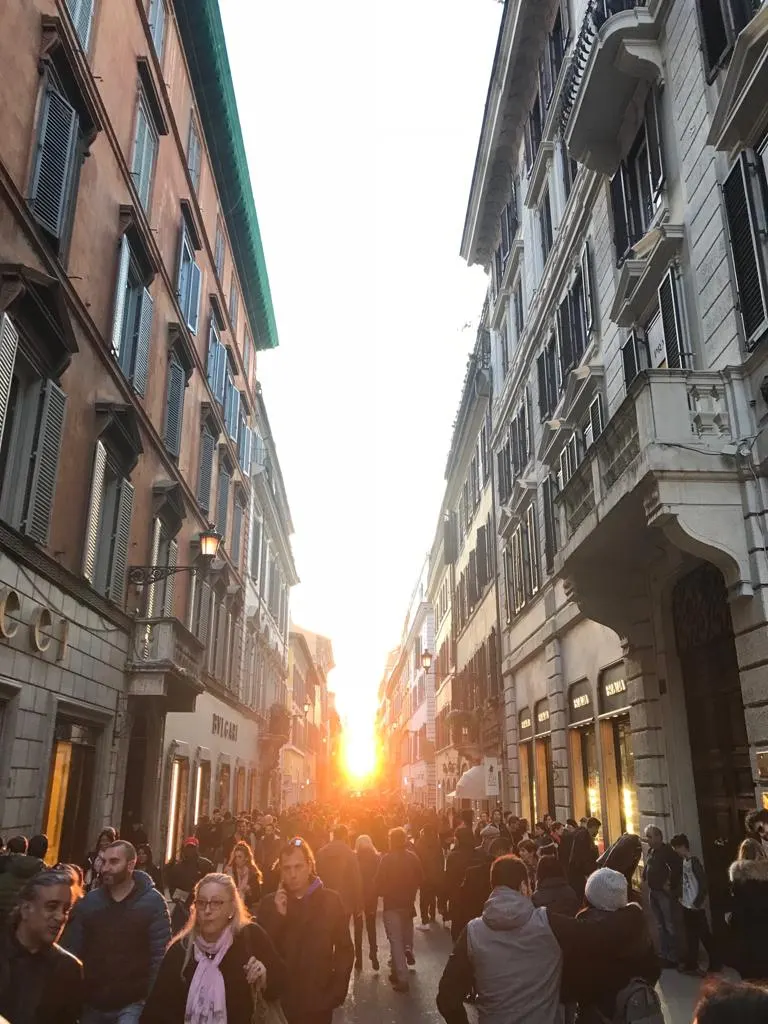 A narrow street at sunset with people walking