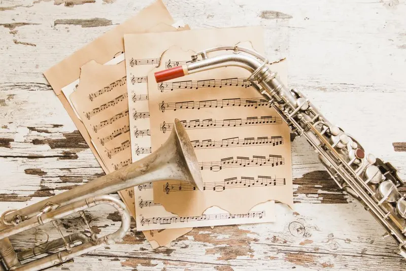 Sheet music and a saxophone on a whitewashed wooden surface